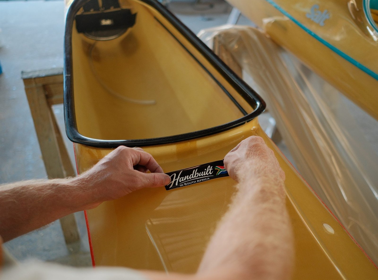 Aplicando el adhesivo de fabricación sobre el casco de un kayak
